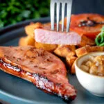 Cider glazed cut open bacon chops with fried potatoes, grilled tomato, rocket and apple chutney.