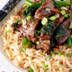 Close up beef and broccoli stir fry served with egg fried rice featuring a title overlay.