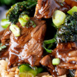 Close up beef and broccoli stir fry garnished with spring onions featuring a title overlay.