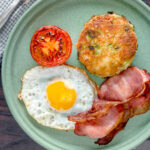 Overhead fried bubble and squeak served with bacon, grilled tomato and fried egg featuring a title overlay.