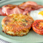 Fried bubble and squeak patty served with bacon, grilled tomato and fried egg.