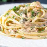 Canned salmon pasta with linguini, cornichons and dill featuring a title overlay.