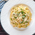 Overhead canned salmon linguini pasta with creme fraiche and cornichons.