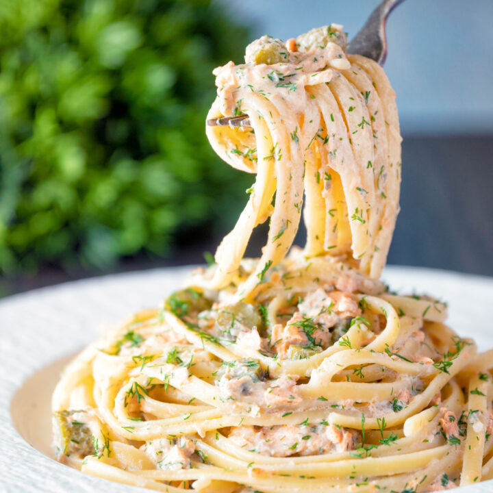 Canned salmon pasta with creme fraiche, cornichons and a fresh dill garnish on a fork.