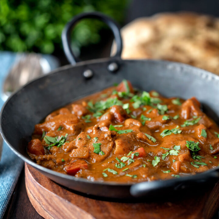 Chicken balti curry served in and iron karahi with a naan bread.