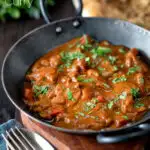 Chicken balti curry served in and iron karahi with fresh coriander featuring a title overlay.