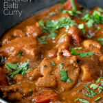 Close up chicken balti curry served in and iron karahi with fresh coriander featuring a title overlay.