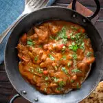 Overhead Chicken balti curry served in and iron karahi and a naan bread featuring a title overlay.