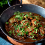 British Indian chicken jalfrezi curry with fresh coriander served in an iron karai.