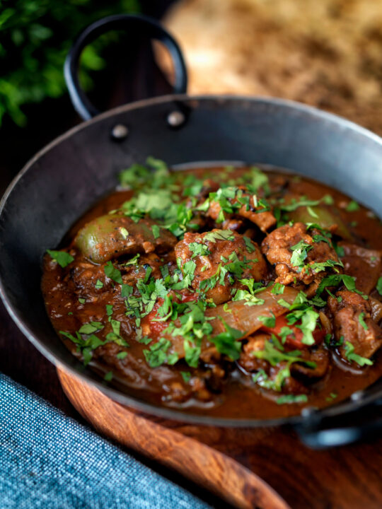 British Indian chicken jalfrezi curry with fresh coriander served in an iron karai.