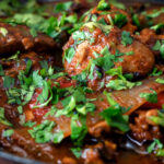 Clos up British Indian chicken jalfrezi curry with fresh coriander served in an iron karai.