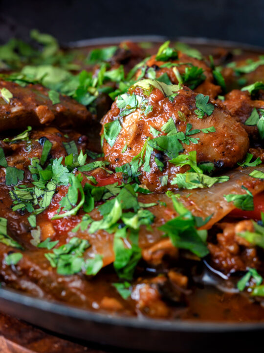 Clos up British Indian chicken jalfrezi curry with fresh coriander served in an iron karai.