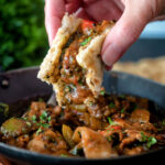 British Indian chicken jalfrezi curry being scooped up with a tandoori naan bread.