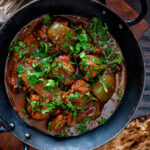 Overhead British Indian chicken jalfrezi curry with fresh coriander served in an iron karai.