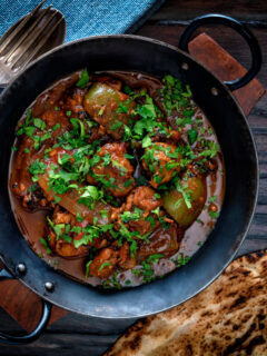 Overhead British Indian chicken jalfrezi curry with fresh coriander served in an iron karai.