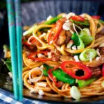 Chicken satay stir fry with peanuts and egg noodles featuring a title overlay.