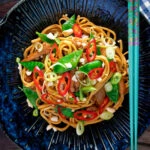 Overhead chicken satay stir fry with peanuts and egg noodles.