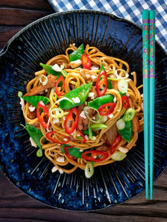 Overhead chicken satay stir fry with peanuts and egg noodles.