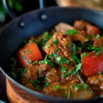 Close up Indian influenced lamb jalfrezi curry with red peppers garnished with fresh coriander.