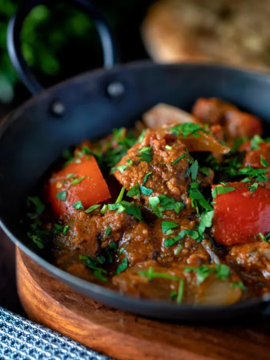 Close up Indian influenced jalfrezi gosht curry with red peppers garnished with fresh coriander.