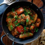 Overhead Indian influenced lamb jalfrezi curry served with a naan bread.