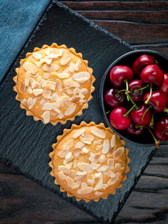 Overhead mini Bakewell tarts with a frangipane filling and almond topping.