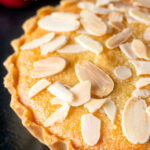 Close up mini Bakewell tarts with a frangipane filling and almond topping featuring a title overlay.