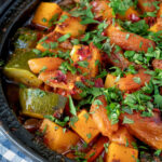 Close up Moroccan influenced vegan vegetable tagine with squash and courgette featuring a title overlay.