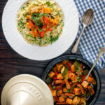 Overhead Moroccan influenced vegan vegetable tagine with squash and courgette served with buttered couscous.