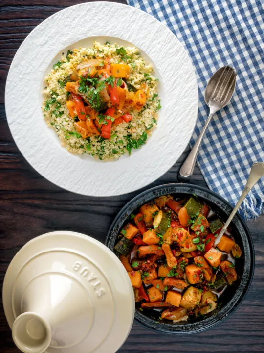 Overhead Moroccan influenced vegan vegetable tagine with squash and courgette served with buttered couscous.