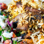 Close up vegan mushroom biryani served with raita and kachumber salad on a plate.