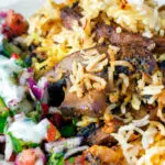 Close up vegan mushroom biryani served with raita and kachumber salad on a plate.
