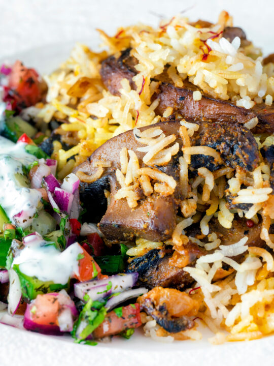 Close up vegan mushroom biryani served with raita and kachumber salad on a plate.