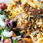 Close up vegan mushroom biryani served with raita and kachumber salad on a plate featuring a title overlay.