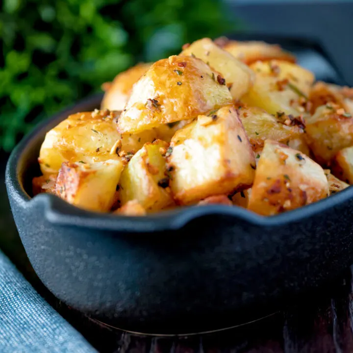 Parmentier potatoes or mini roast potatoes with garlic and rosemary served in an stoneware bowl.