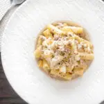Overhead pasta alla norcina with black pepper and fresh parmesan cheese.