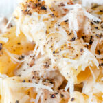 Close up pasta alla norcina with black pepper and fresh parmesan cheese featuring a title overlay.