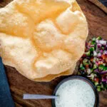 Overhead Indian poppadoms or papad served with kachumber salad and mint raita.