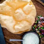 Overhead Indian poppadoms or papad served with kachumber salad and mint raita featuring a title overlay.