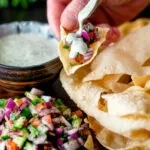 Indian poppadoms being topped with kachumber salad and a mint & yoghurt raita.