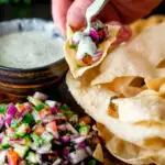 Indian poppadoms being topped with kachumber salad and a mint & yoghurt raita featuring a title overlay.