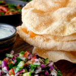 Indian poppadoms or papad served with kachumber salad and mint raita featuring a title overlay.