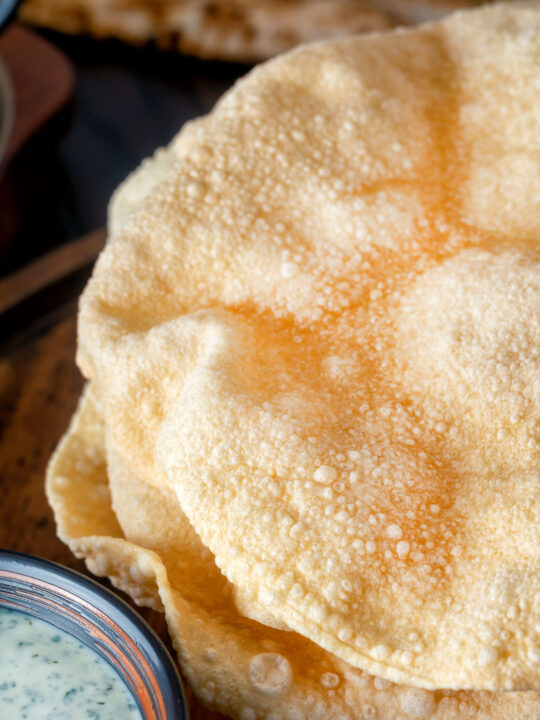 Close up freshly cooked poppadoms or papad served with mint raita.