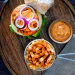 Overhead peri peri chicken burger served with spicy mayonnaise and French fries.
