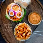 Overhead peri peri chicken burger served with spicy mayonnaise and French fries featuring a title overlay.