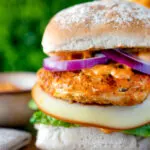 Peri peri chicken burger served with red onion and smoked cheese.
