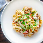 Overhead braised rabbit ragu served with orecchiette pasta and fresh parsley featuring a title overlay.