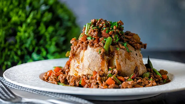 Savoury minced beef with green beans served over a baked potato.