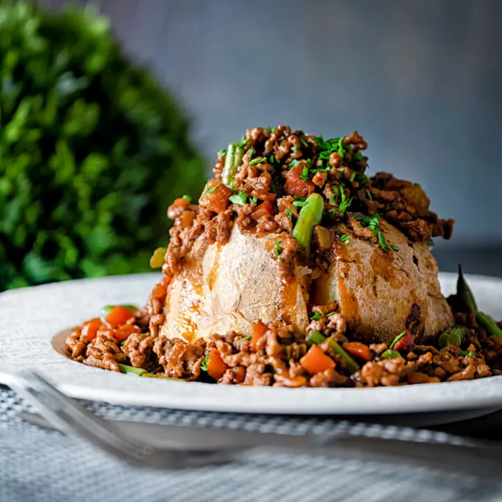 Savoury minced beef with green beans served over a baked potato.