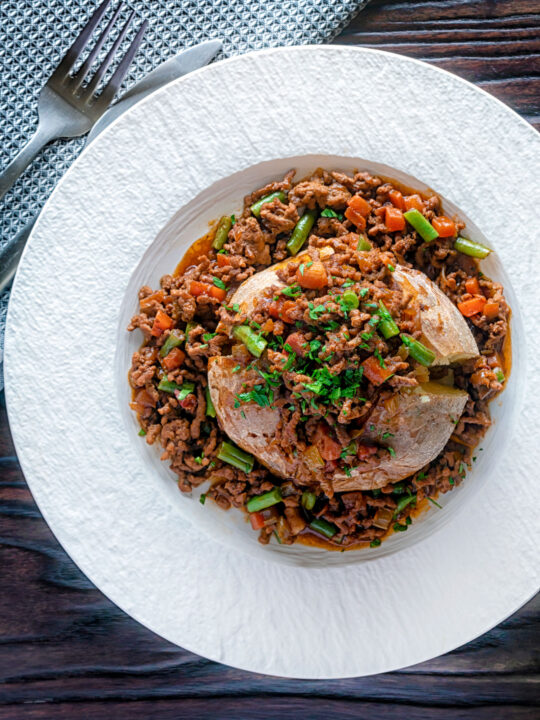 Overhead savoury minced beef with green beans served over a jacket potato.